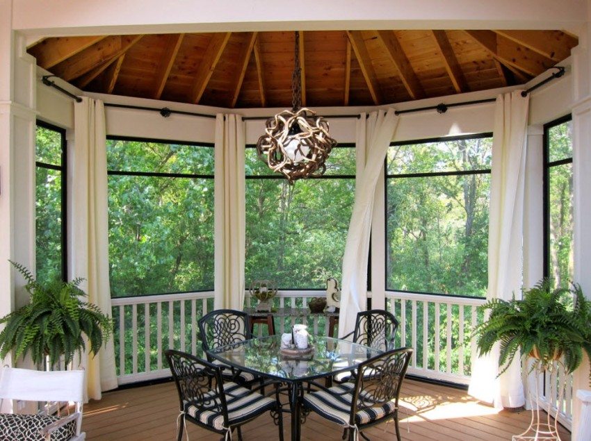Forged chairs and a table are placed inside the glazed gazebo