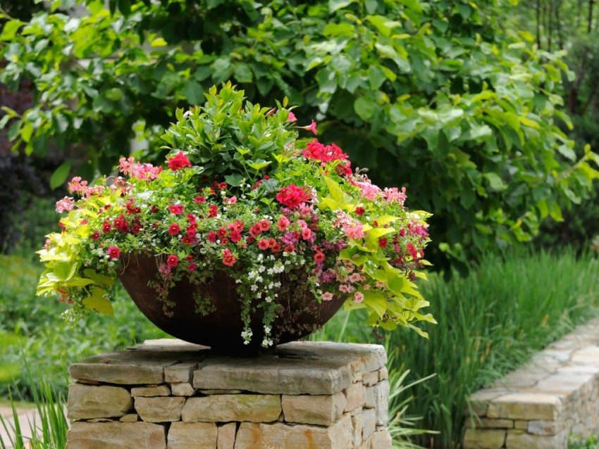 A stone fence decorates a flowerpot with garden flowers