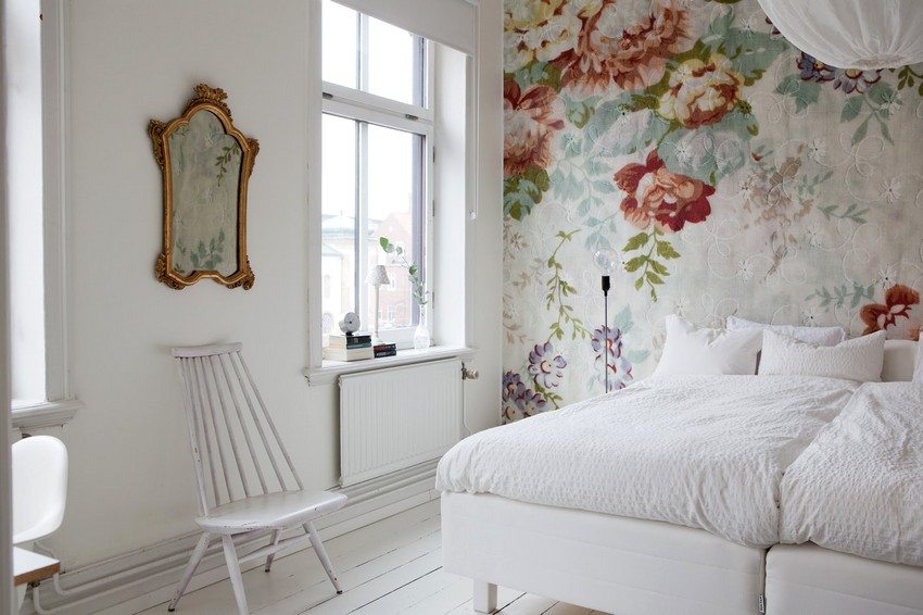 Wallpaper with a pattern is pasted over the wall behind the bed