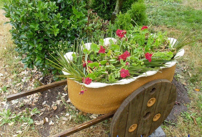Et blomsterbed laget av et bildekk i form av en hagevogn