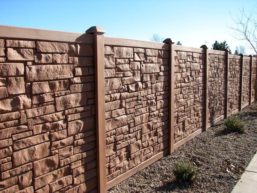Fence made of concrete panels with imitation of stone, covered with paint