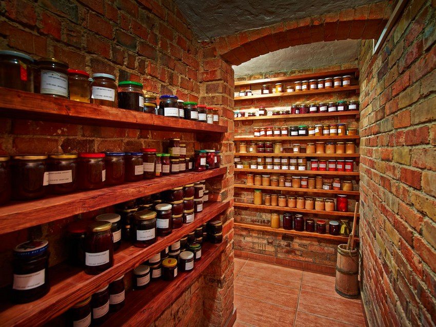 There are wooden shelves along the walls of the cellar