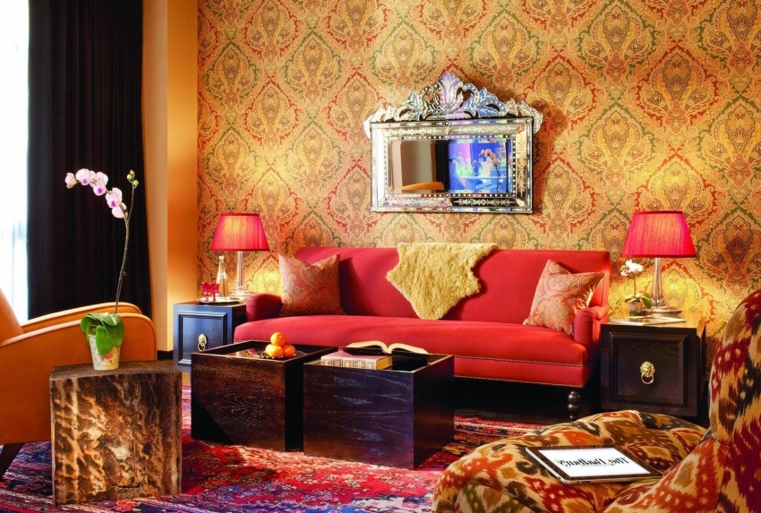 Orientální styl v designu obývacího pokoje zahrnuje použití tapet v teplých barvách se zlatými nebo červenými ornamenty