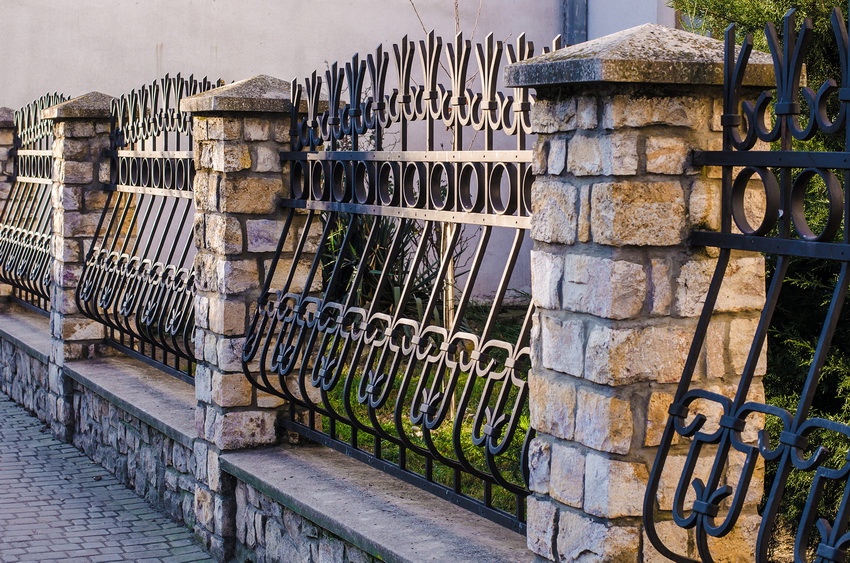 Korištenje krivotvorenih dijelova ograde i kamenih temelja vrlo je popularna opcija ograde.