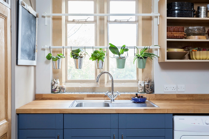 There is a sink and an area for growing flowers near the window in the kitchen